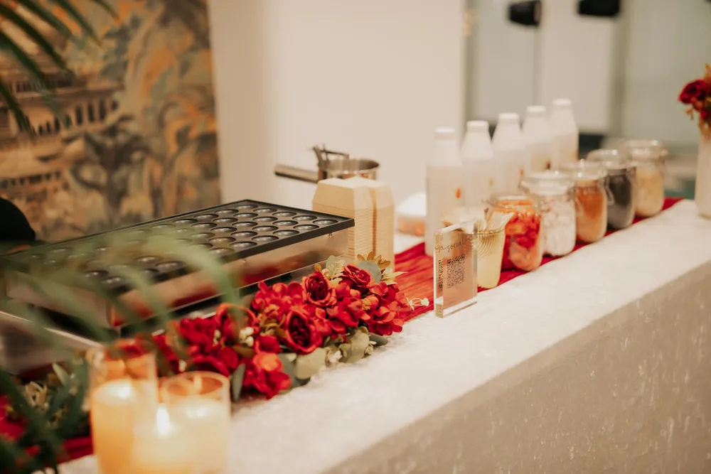 Pancake griddle and red floral display beside a row of topping jars